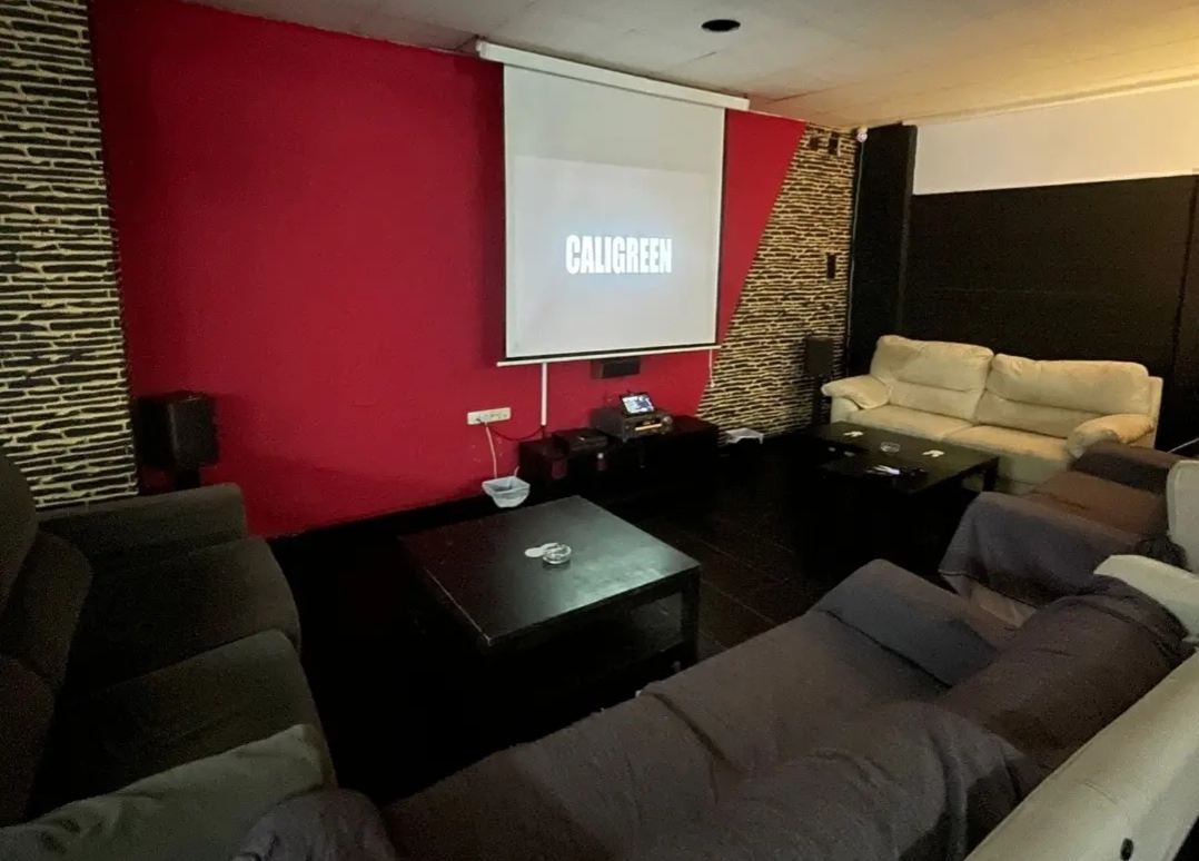 Cannabis club lounge interior with seating and a projection screen